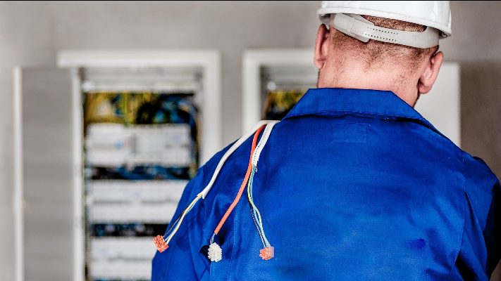 electrician carries electrical wires over his shoulder.