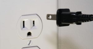 A cord being plugged into a wall socket.