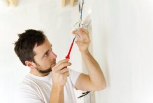 An electrician works to wire a lightbulb.